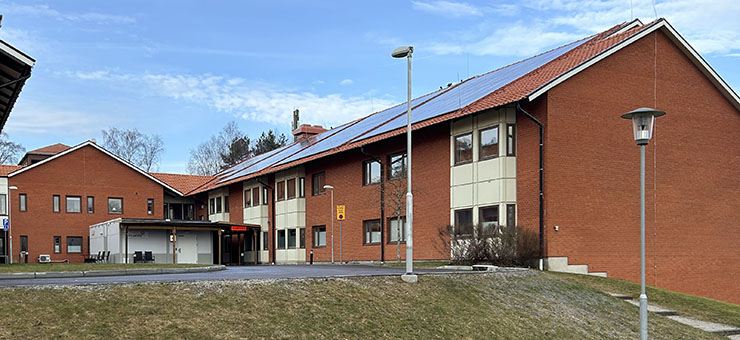 Ingången till habiliteringsmoIngång till Habiliteringsmottagning barn och unga Hässleholm. Det är en röd tegelbyggnad. Det går en stentrappa uppför en slänt.