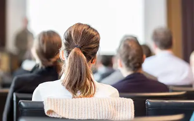 Flera personer sitter vända mot en person som står och pratar.