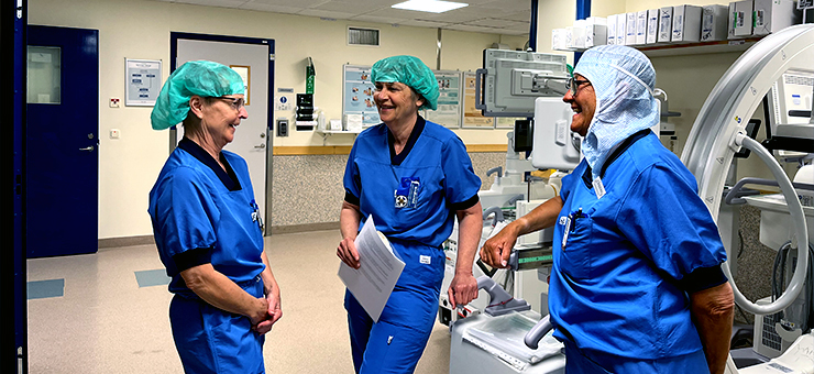 Christina Olander pratar med kollegorna Christel och Marianne. De är klädda i blå operationskläder.