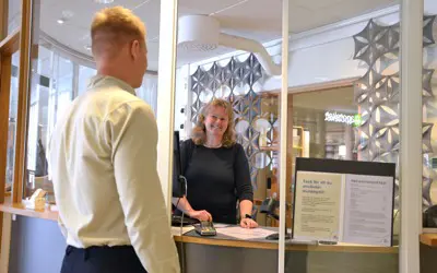 En besökare pratar med personalen i receptionen.