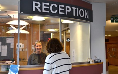 En besökare pratar med personalen i receptionen.