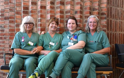 Fyra sjuksköterskor sitter på en bänk.